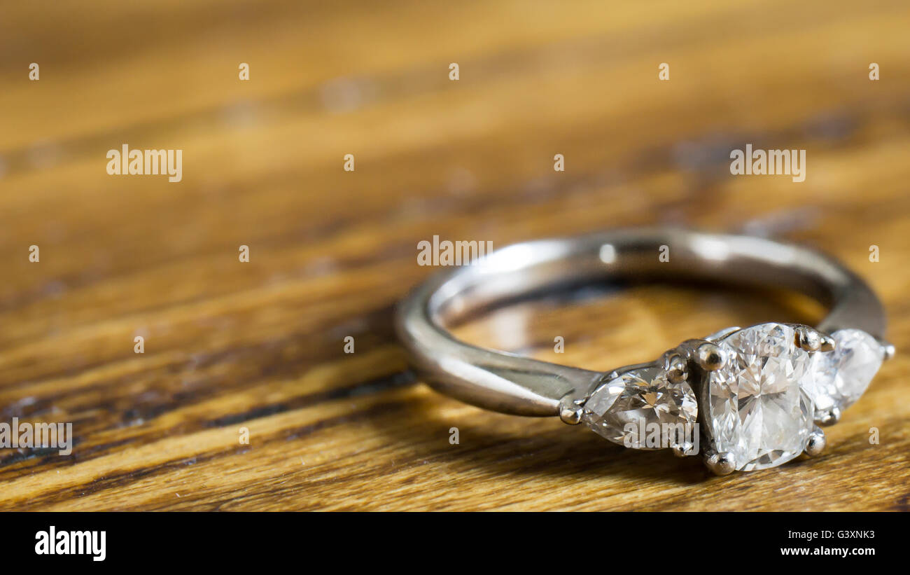 3 stone trinity white gold diamond engagement ring on rustic oak bench