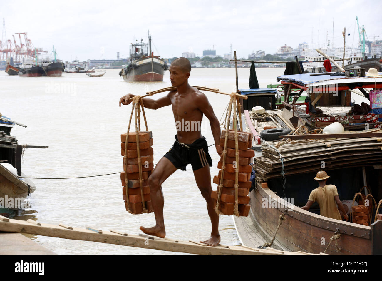 Yangon, Myanmar. 16th June, 2016. A labor carries bricks at a jetty on ...