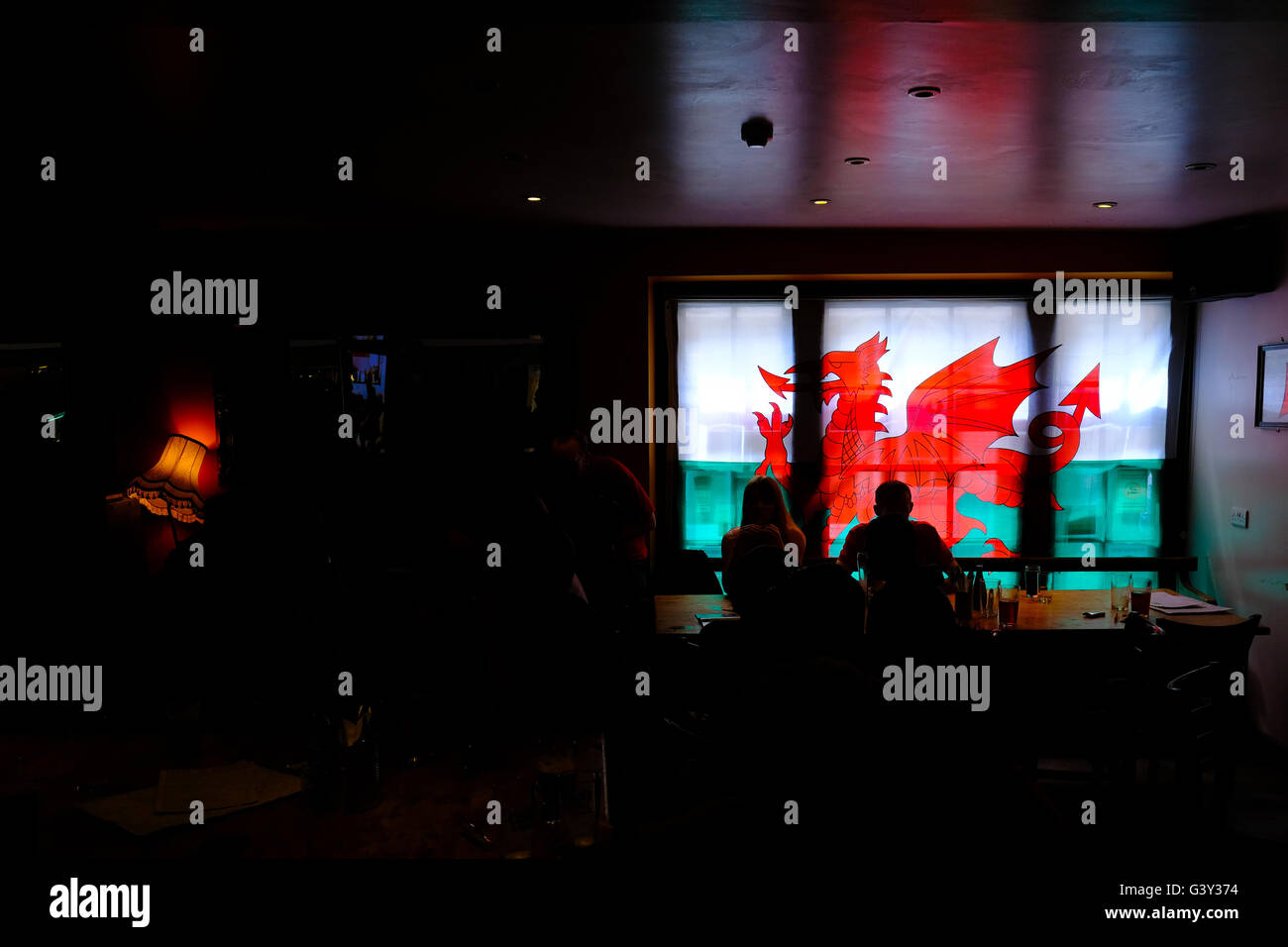 Aberystwyth, Wales, UK. 16 June 2016. A Welsh flag hangs in the window of a pub in Aberystwyth as fans sit in the gloom after a 2:1 loss to England in today's EURO match Credit:  Alan Hale/Alamy Live News Stock Photo
