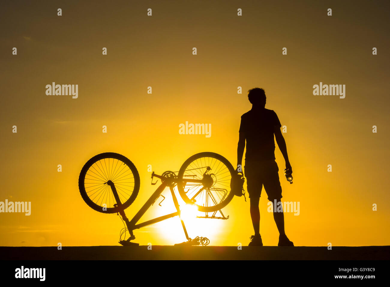 Mountain biker watching the sunrise over the ocean. Stock Photo