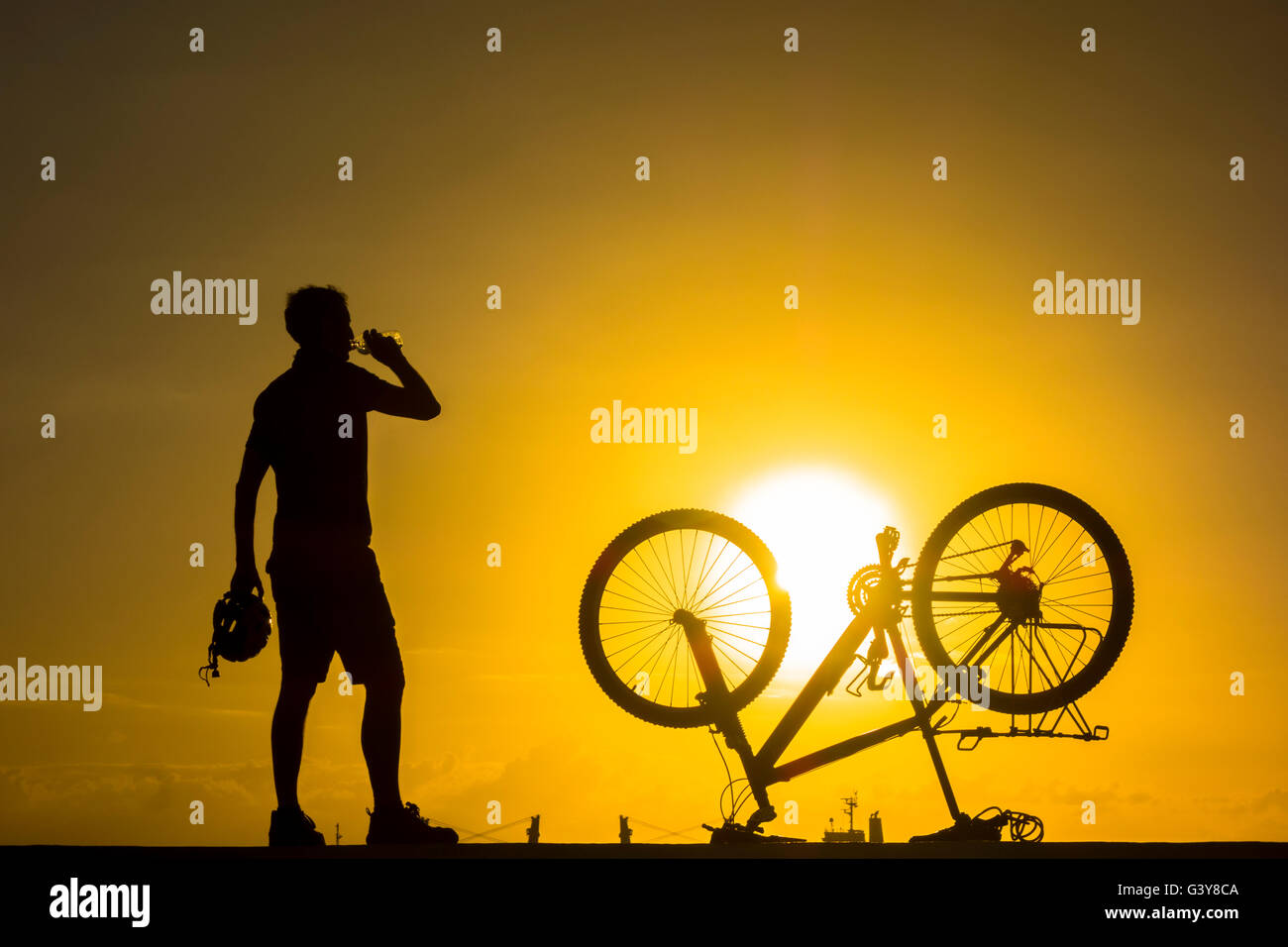 Mountain biker watching the sunrise over the ocean. Stock Photo