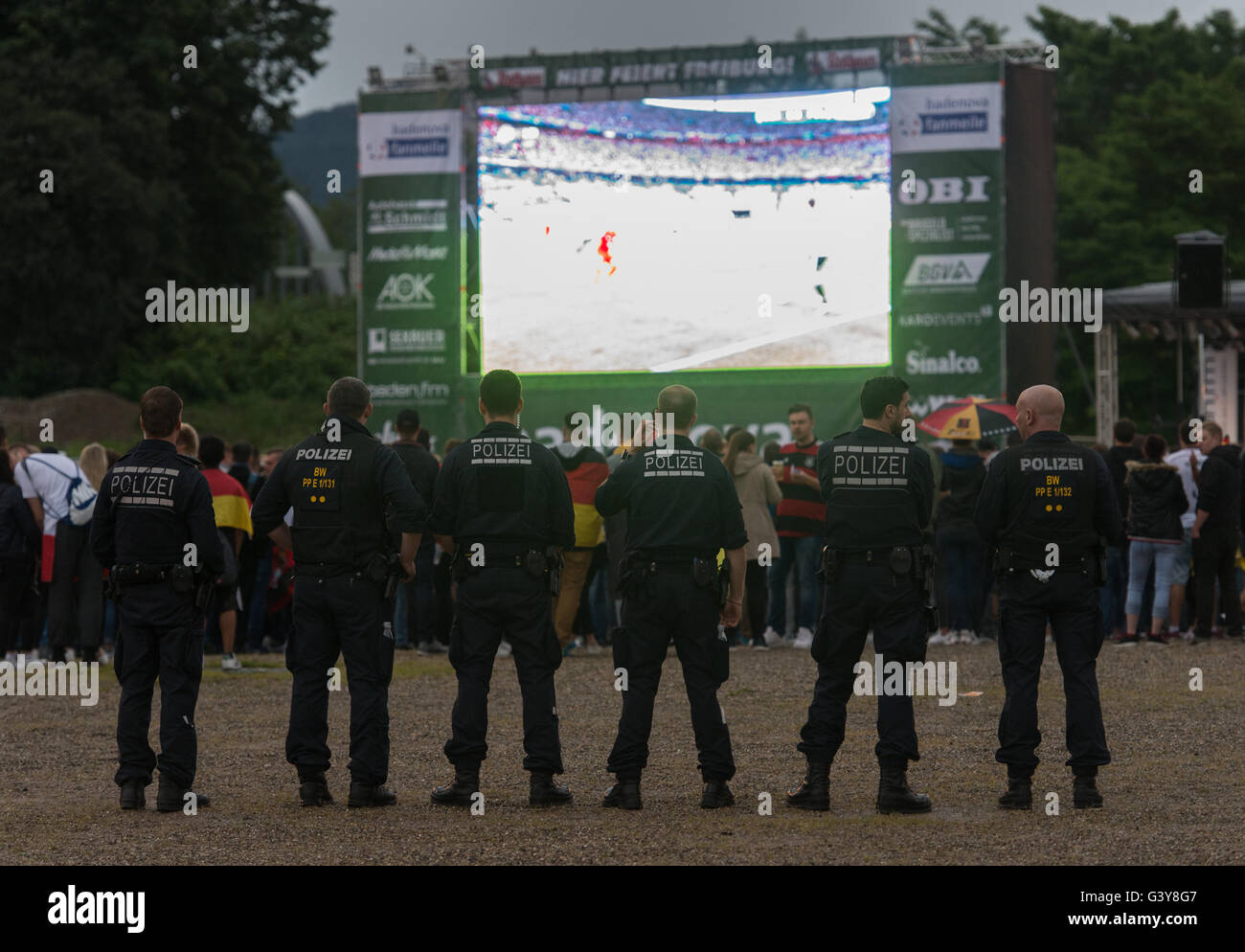 Freiburg, Germany. 16th June, 2016. Policeman watch the soccer match Germany vs Poland in the rain at a public screening event on the fair grounds in Freiburg, Germany, 16 June 2016. Photo: Patrick Seeger/dpa/Alamy Live News Stock Photo