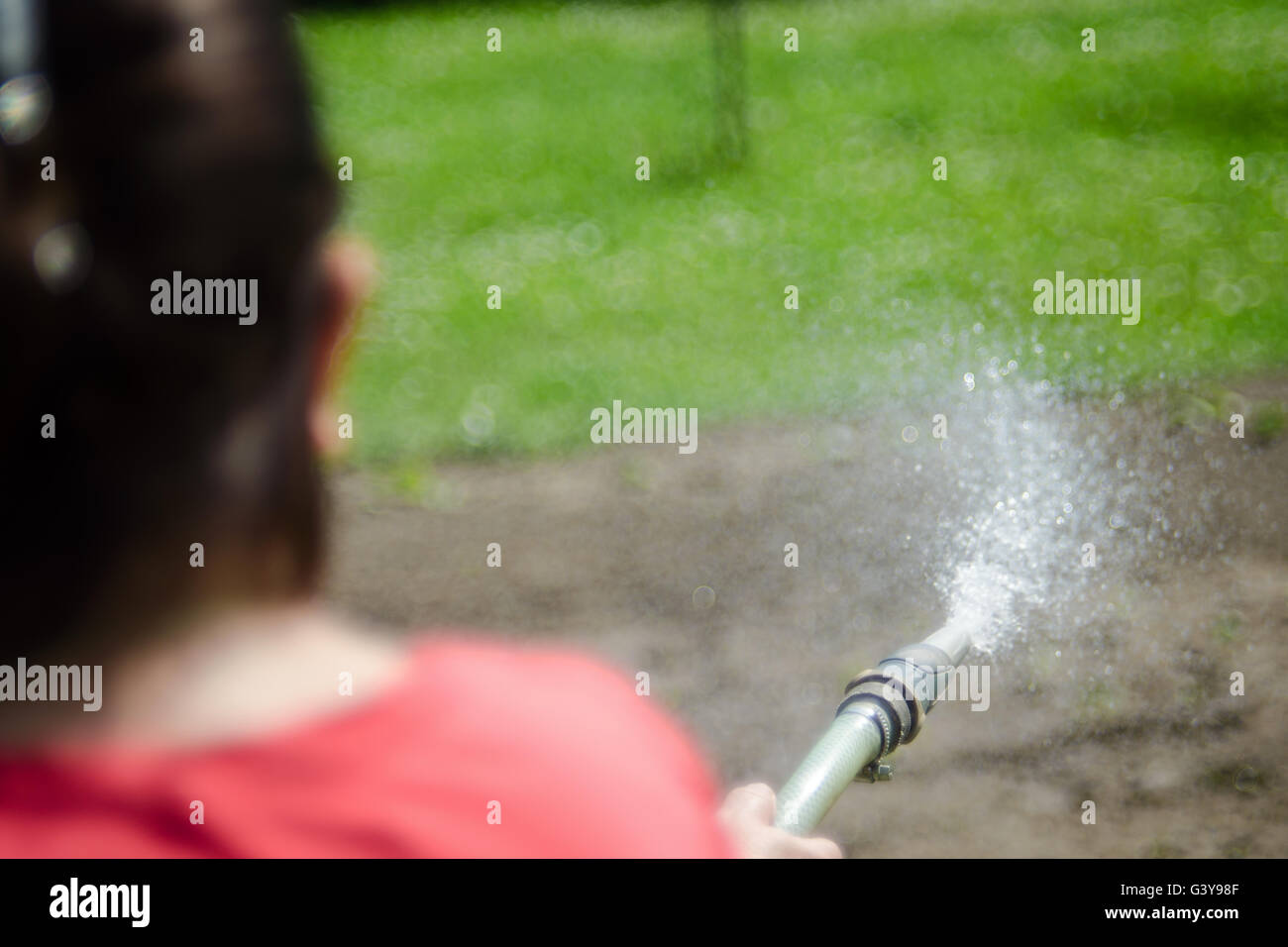 Woman is watering garden. Focus on the water drops. Stock Photo