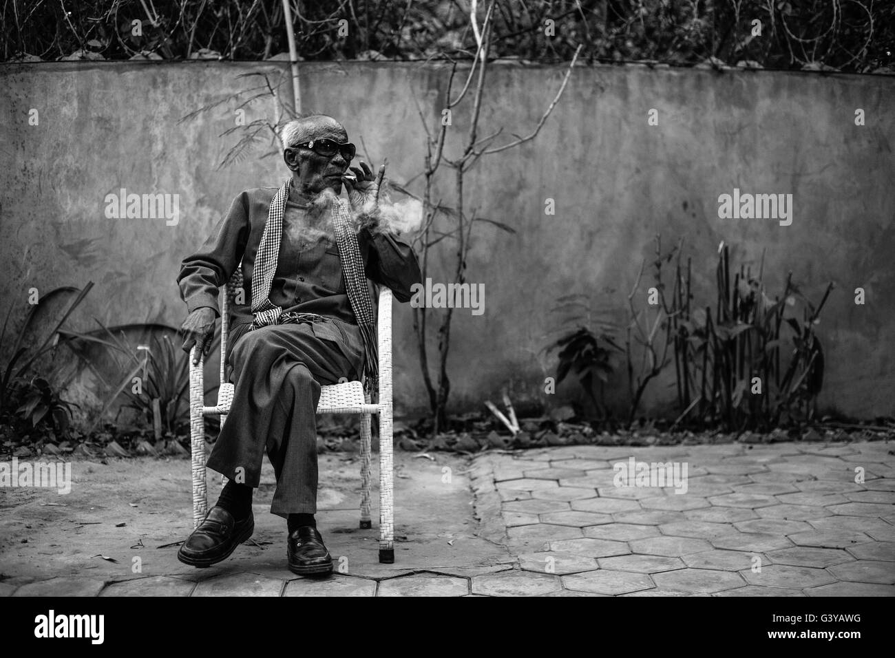 Master Kong Nay, the renowned Cambodian musician, takes five minutes away from a party to smoke a cigarette in peace. Stock Photo