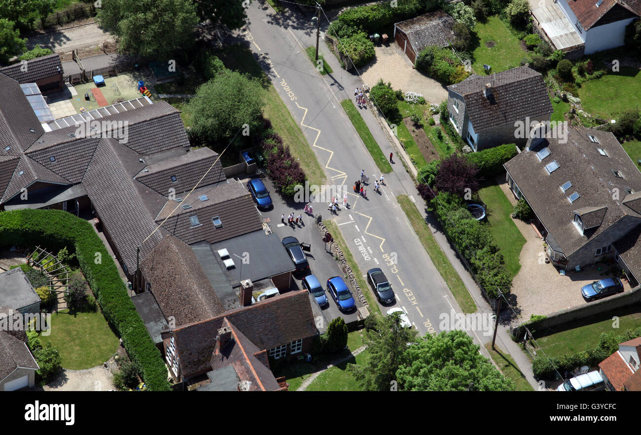 aerial view of a Primary school with supervised children crossing the road, UK Stock Photo