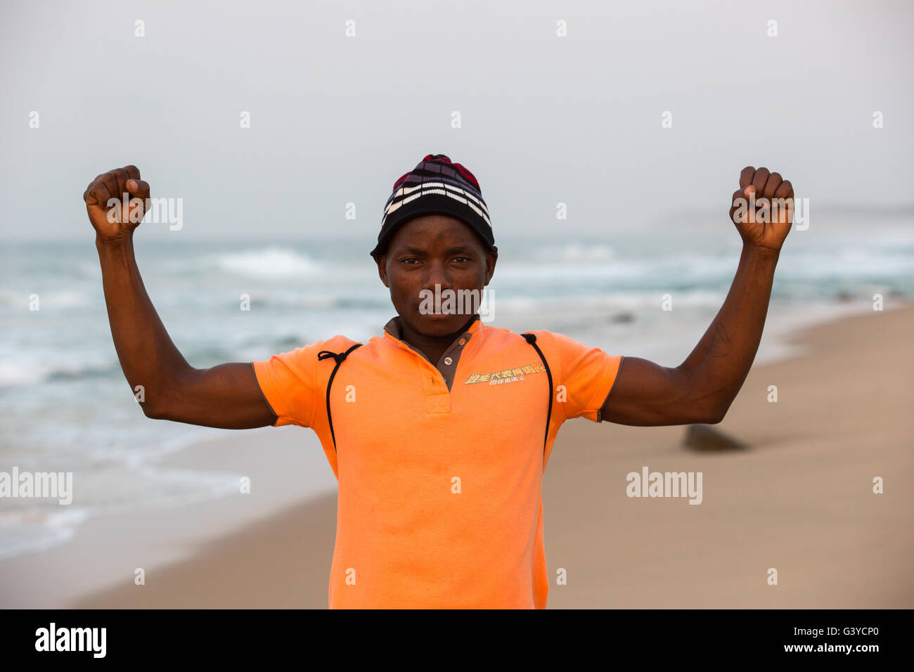 Mozambique local man standing on the beach facing the camera with fists clenched showing his strength Stock Photo