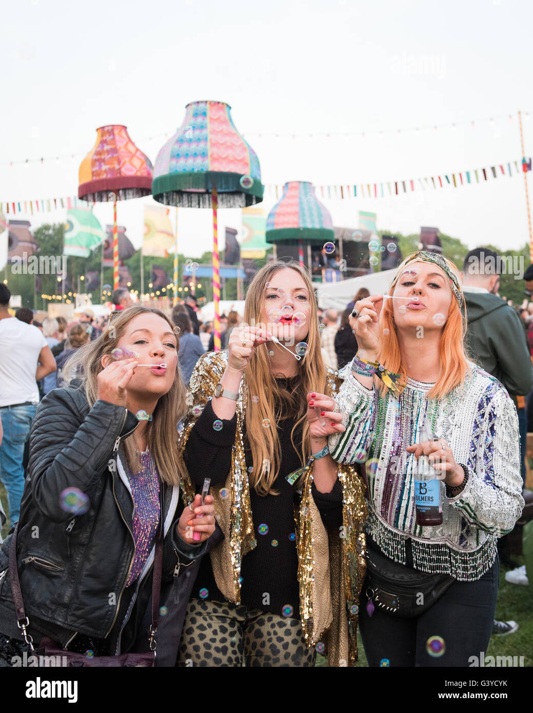 Girls in colourful clothes blowing bubbles at music festival Stock Photo
