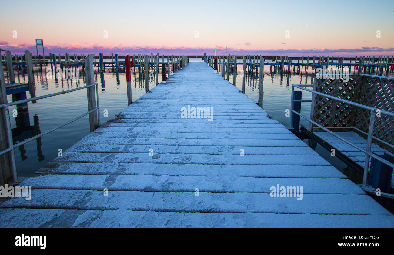 Winter On The Great Lakes. Snow covered pier extends to sunrise horizon on the Great Lakes coast in Michigan. Stock Photo