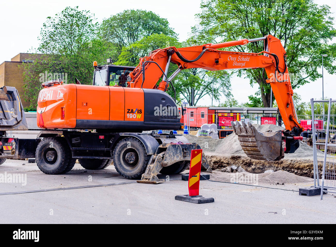 Karlskrona, Sweden - June 16, 2016: Orange Hitachi Zaxis 190W excavator digging out stones from a hole in a parking lot at Potth Stock Photo