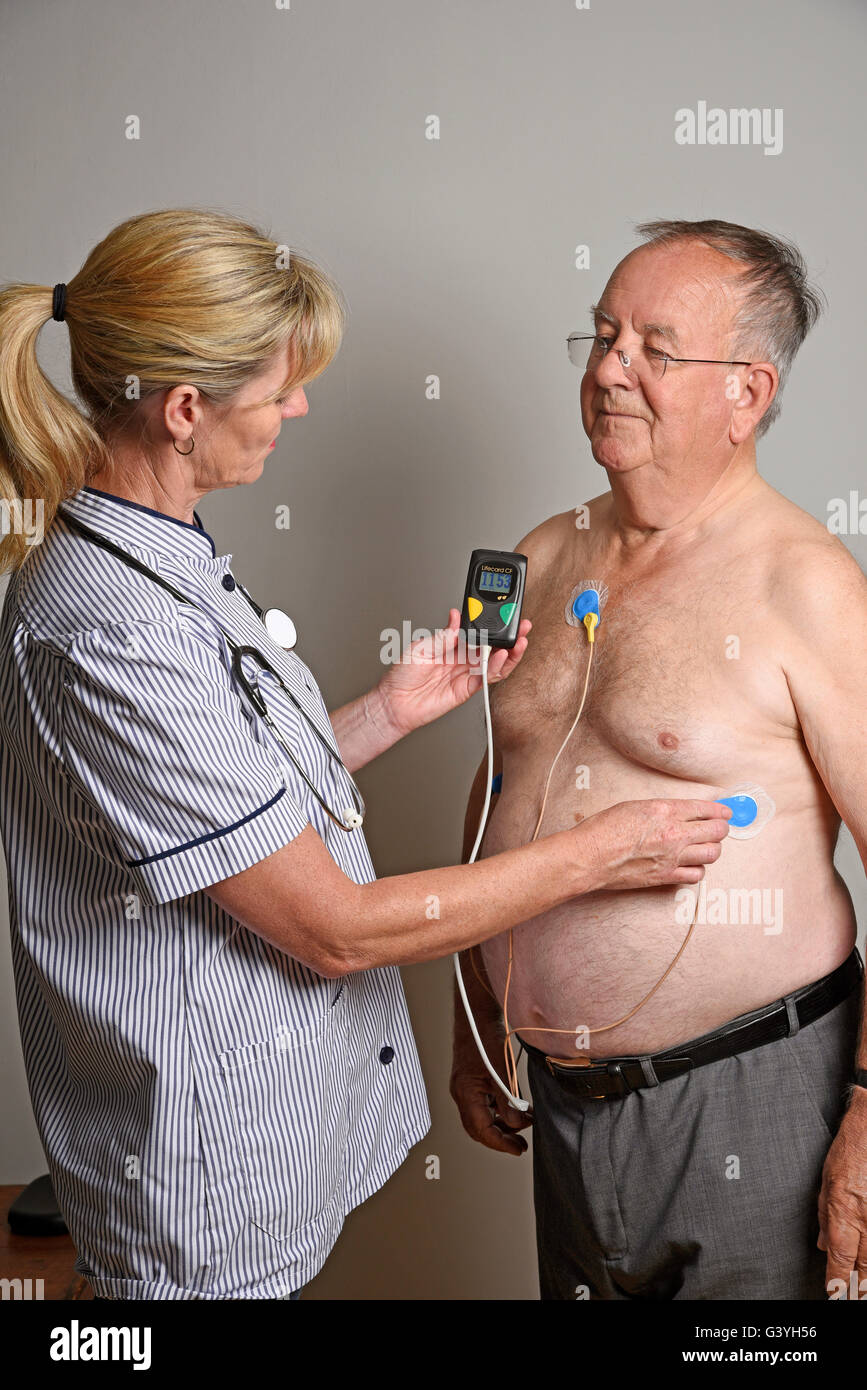 Member of a hospital cardiac measurement team installing a ambulatory ECG monitor to an overweight male patient Stock Photo
