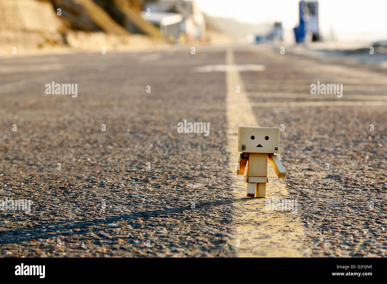 A Danbo Danboard fictional Robot Character walking along the yellow line along the middle of a road Stock Photo