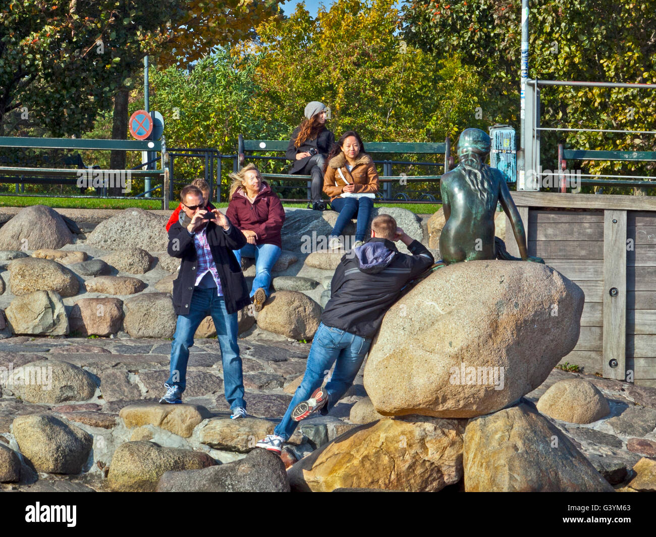 Copenhagen, Denmark:  Tourists playing around The Little Mermaid statue, waterside in Langelinie promenade. Stock Photo