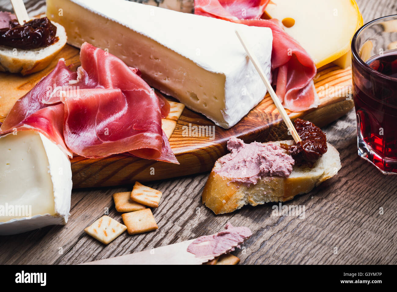 Antipasti platter with different meat and cheese products on wooden