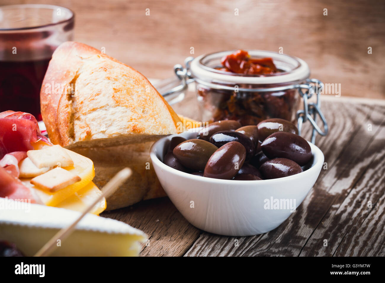 Olives calamata in ceramic bowl on wooden table. Perfect  antipasto starter dish on background antipasti platter Stock Photo