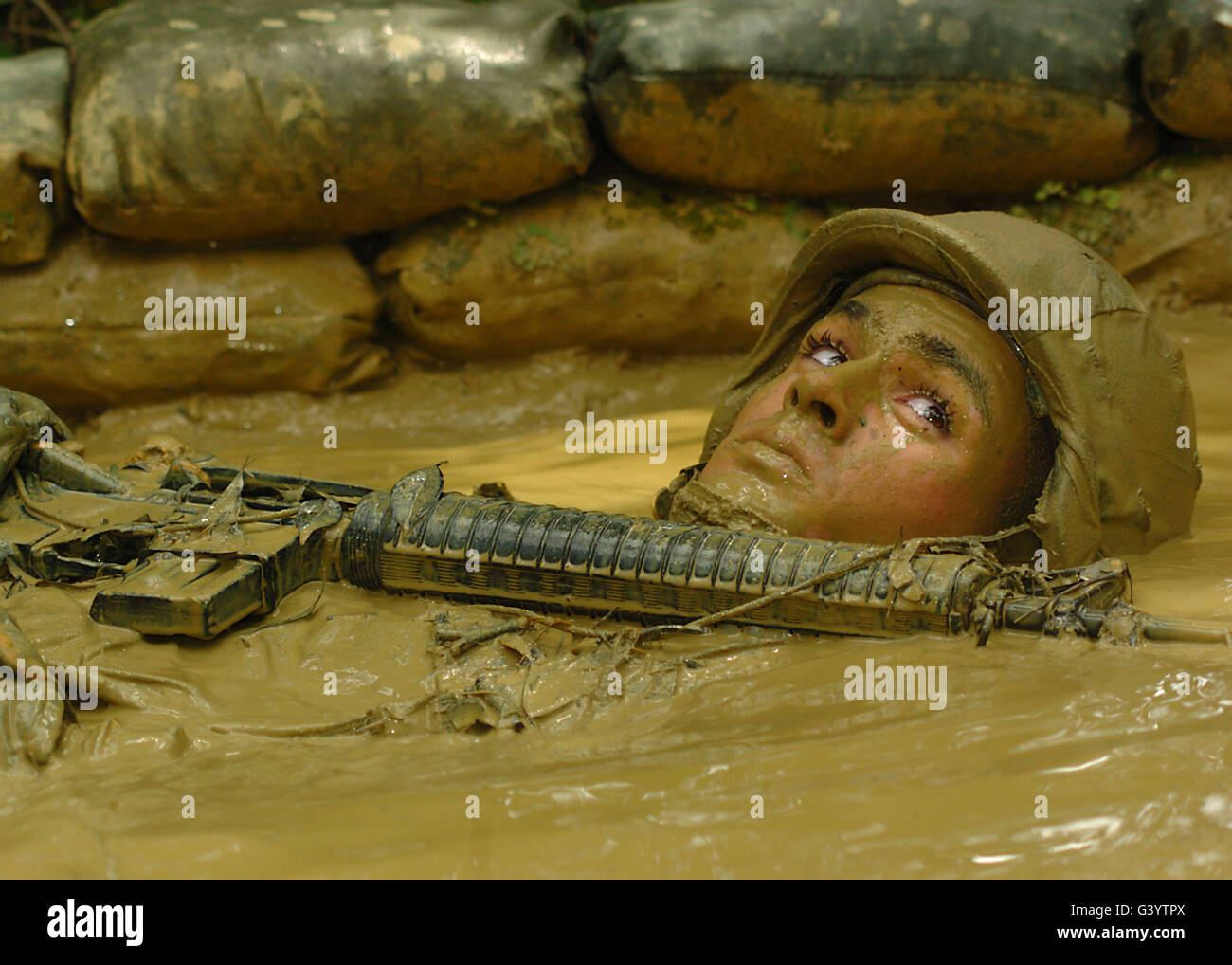 U.S. Navy soldier crawls through mudfilled trenches as part of an