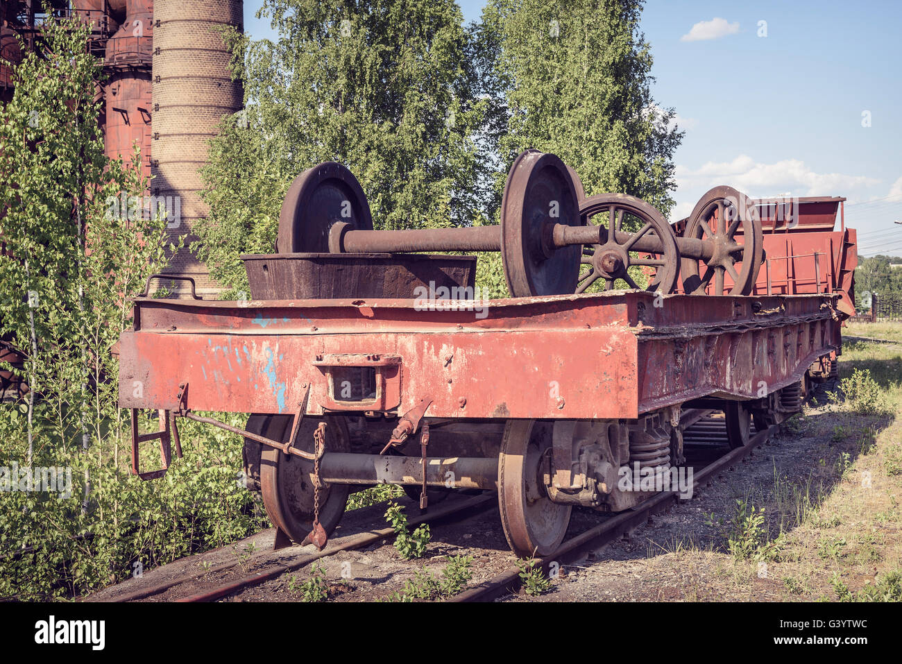 Old flat wagon with railcar wheelset. Old industrial railway cars on on Mining and metallurgical plant Stock Photo