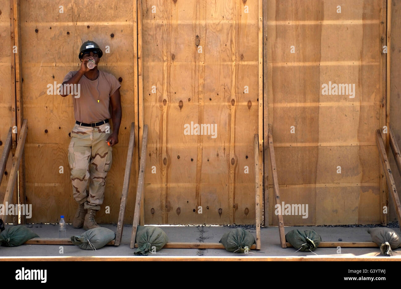 A soldier takes a drink of juice while resting in the shade. Stock Photo