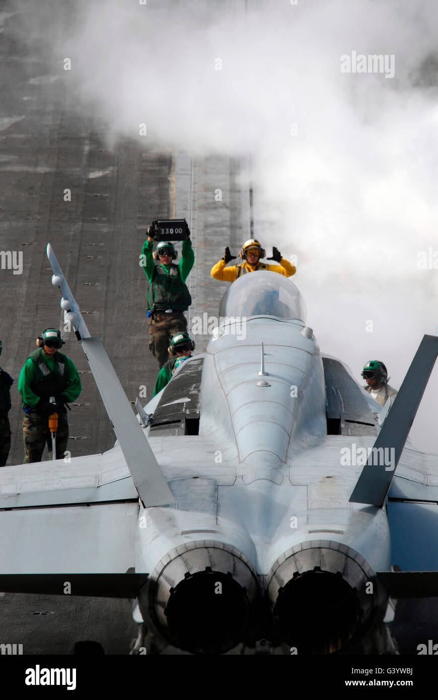 An aircraft handler lines up an F/A-18C Hornet prior to take off. Stock Photo