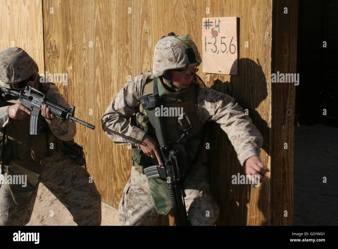 A Marine throws a dummy grenade into a room as his partner provides