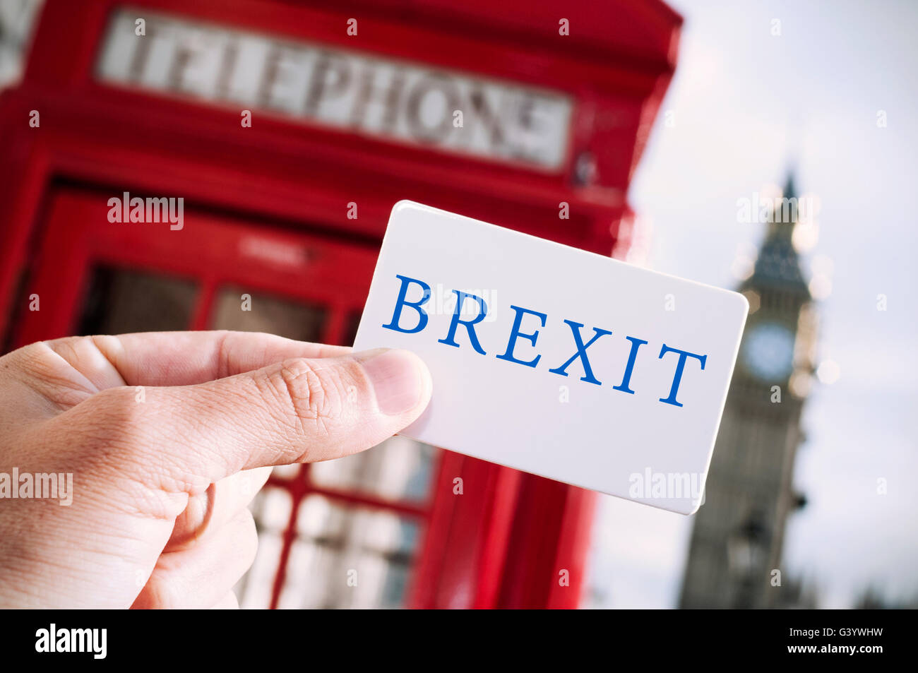 the hand of a young man showing a signboard with the text Brexit with a red telephone booth and the Big Ben in the background, i Stock Photo