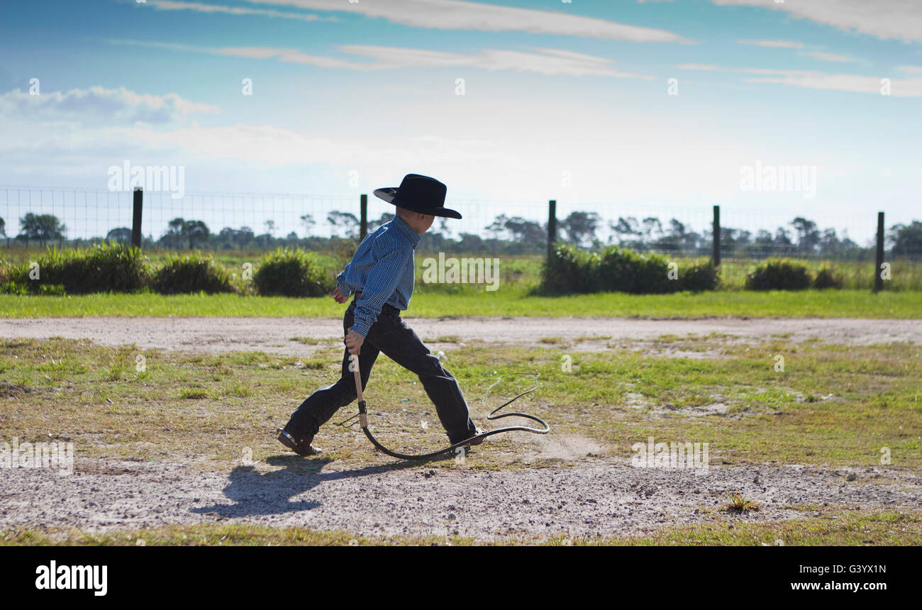 Young Cowboy cracking a bull whip on the Ranch Stock Photo