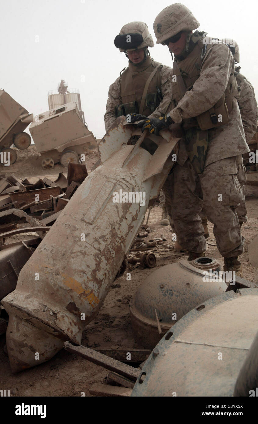 Marines lift up a bomb to determine if it still poses a threat. Stock Photo