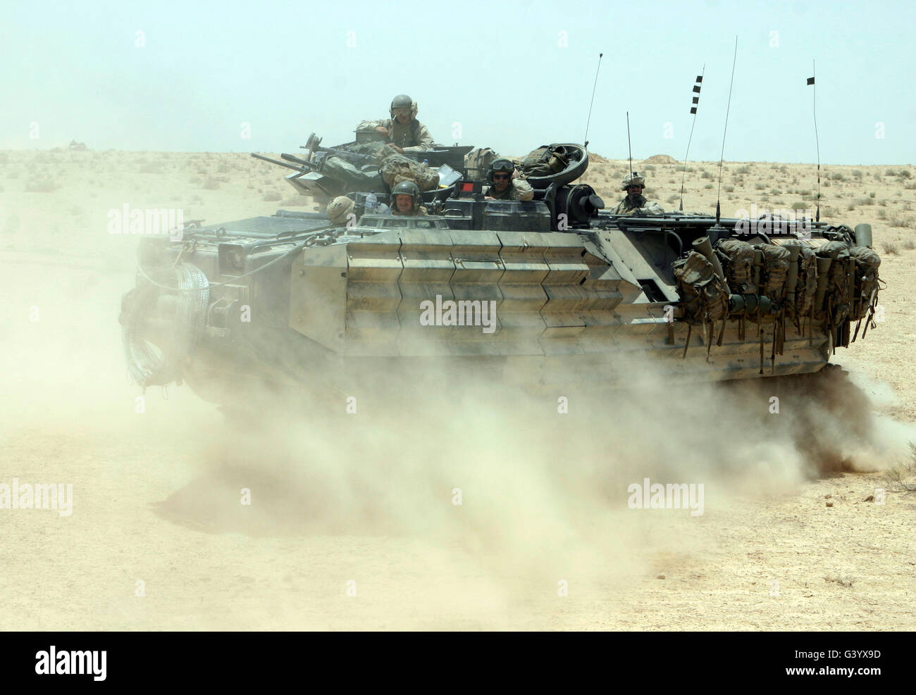 An amphibious assault vehicle kicks up dust as it rumbles through the desert. Stock Photo