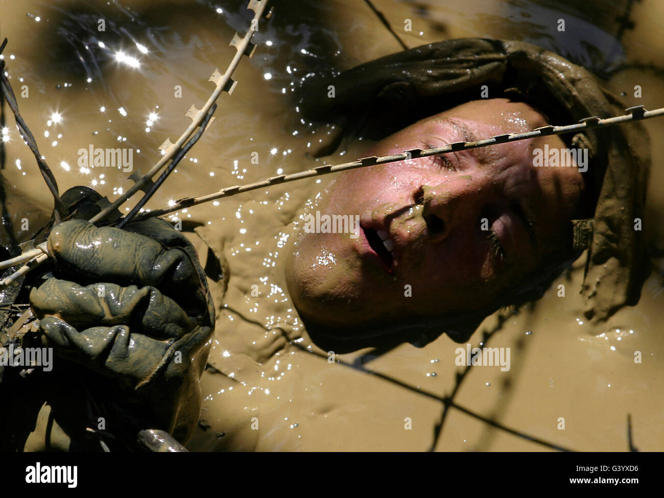 A soldier back crawls through a pit covered in concertina wire. Stock Photo