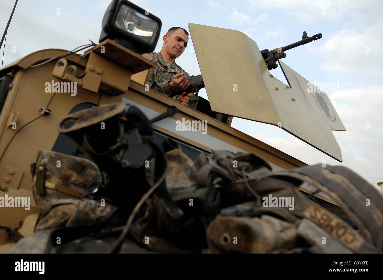 U.S. Army Specialist prepares his weapon atop a humvee. Stock Photo