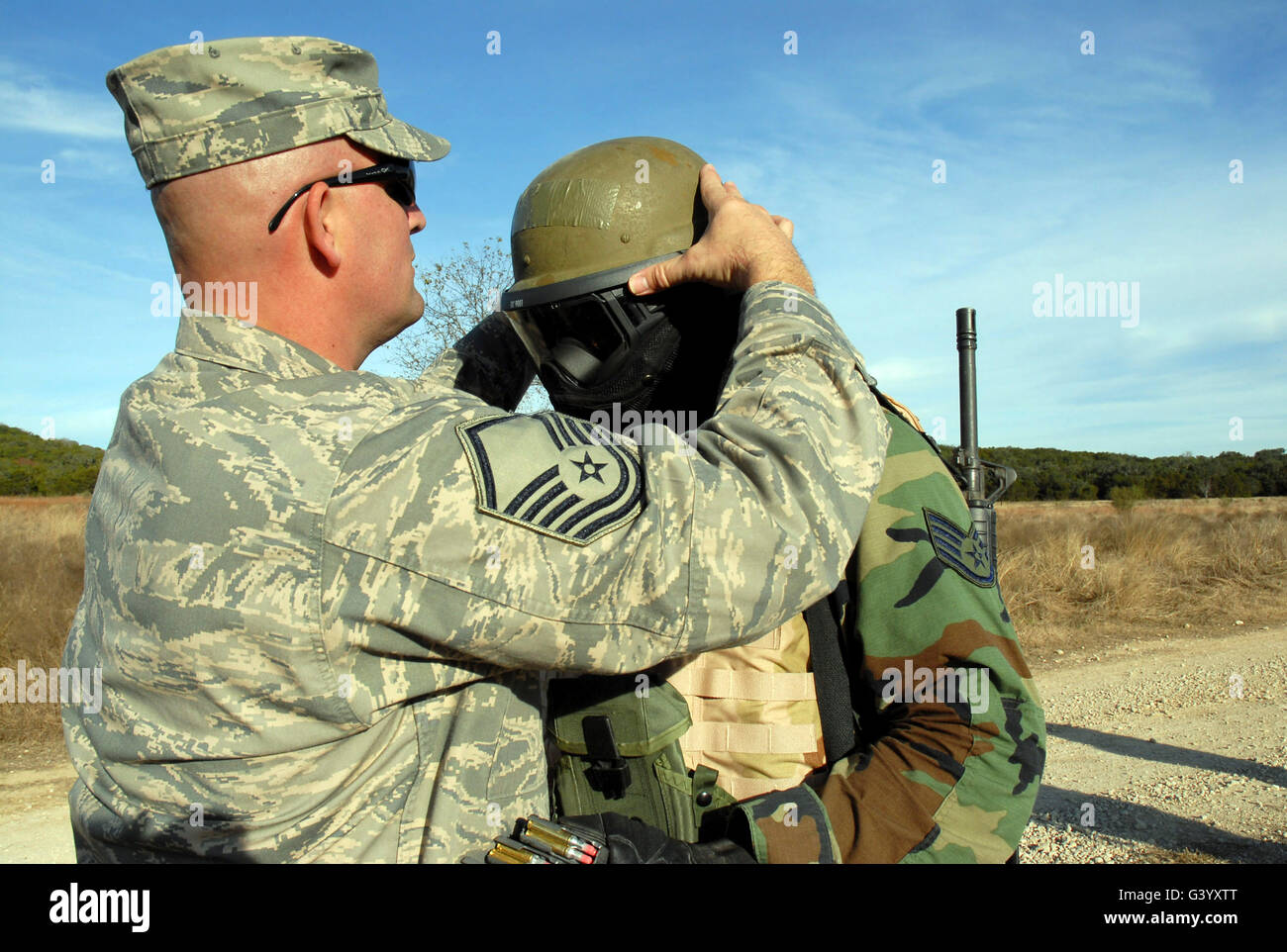 A Sergeant fits a protective mask to a student's helmet. Stock Photo
