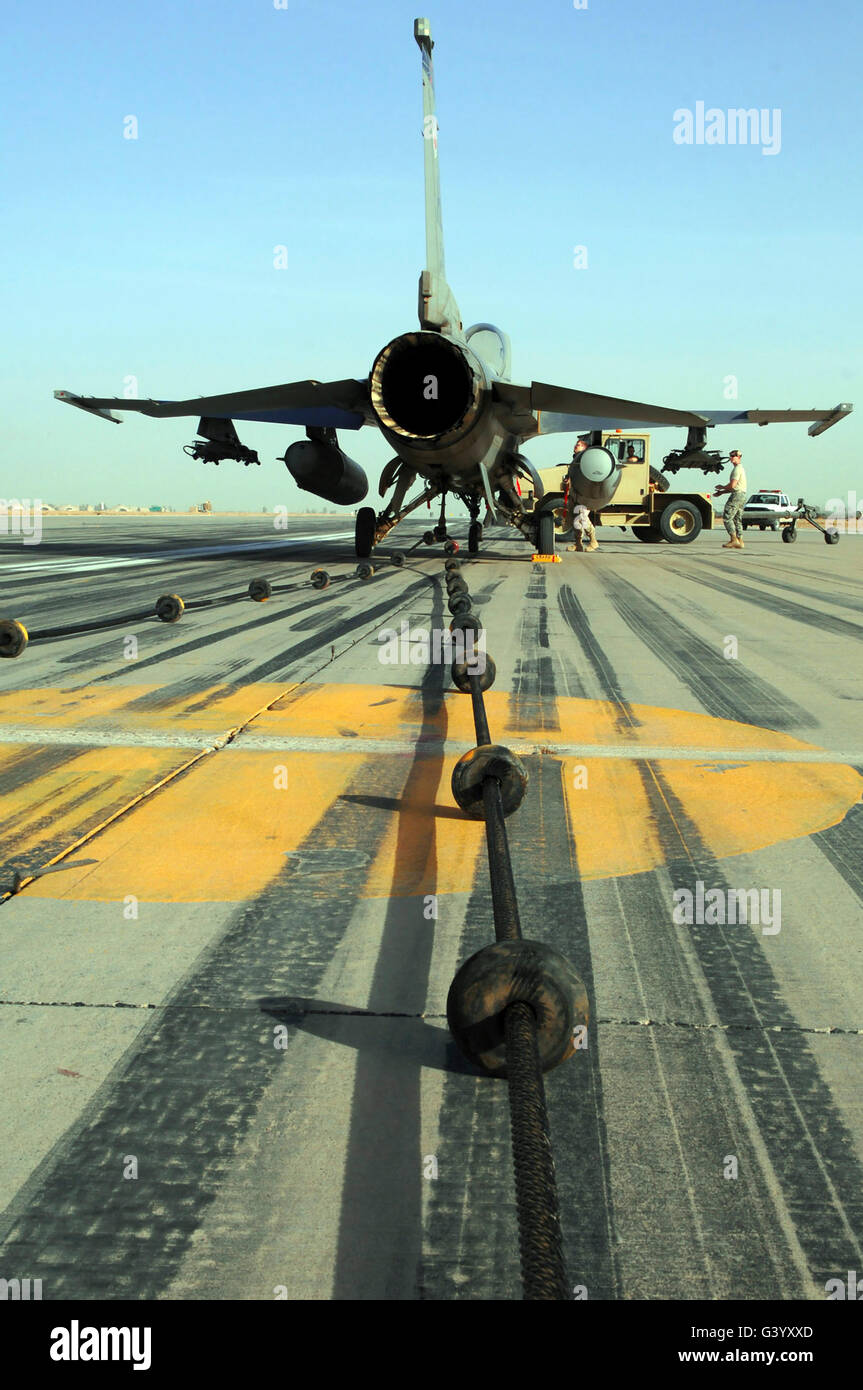 An F-16 Fighting Falcon waits to be disconnected from an emergency arresting barrier system cable. Stock Photo