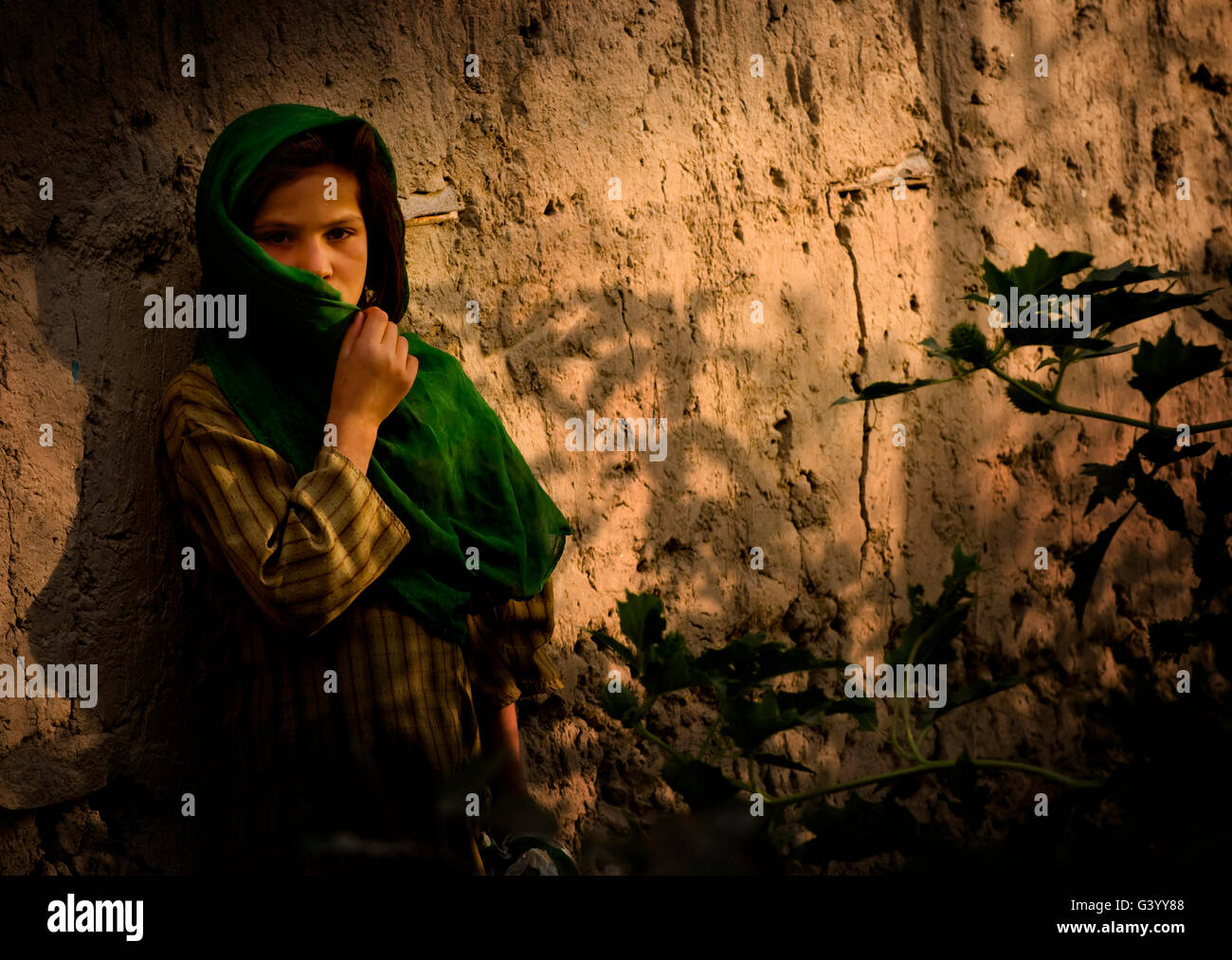 An Afghan girl covers her face from the dusty wind in a village. Stock Photo