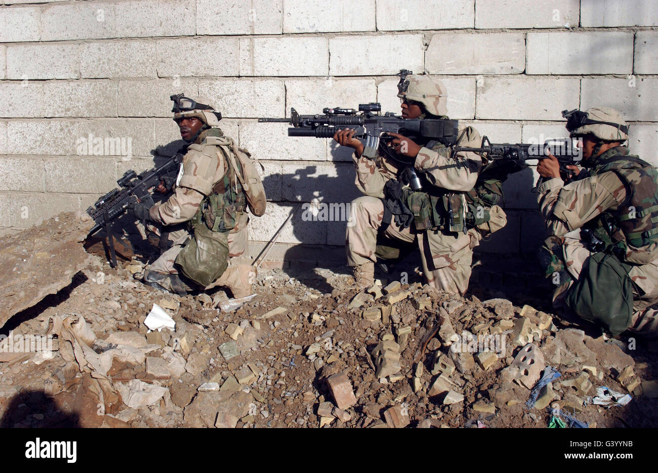 U.S. Army soldiers moving along a wall in Fallujah, Iraq, during Operation al Fajr. Stock Photo