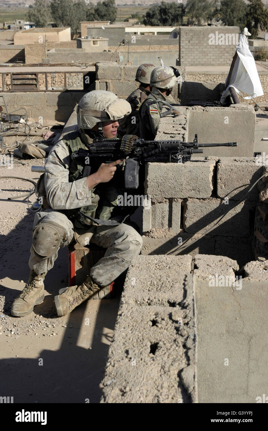 A U.S. Marine and Iraqi Army soldiers watching over the surrounding streets from a rooftop in Karabilah, Iraq. Stock Photo