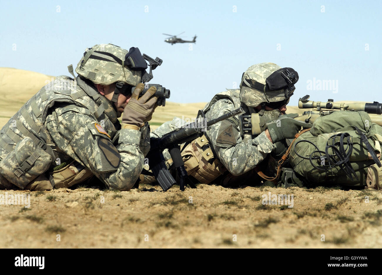 Two U.S. Army soldiers using binoculars and a riflescope to watch for insurgents near the Syrian border in Iraq. Stock Photo