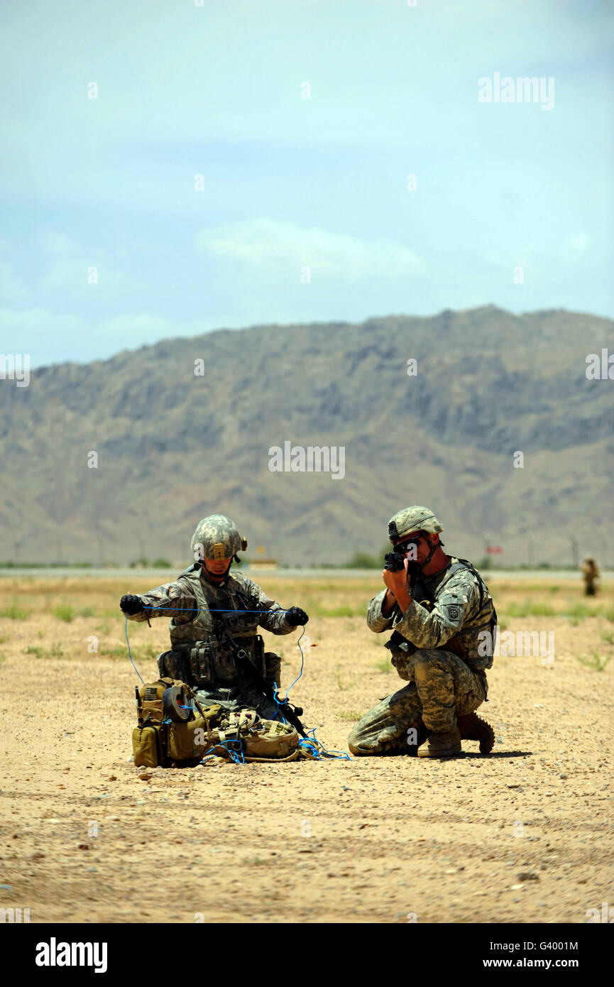 A soldier prepares a drag line while an Army soldier provides cover in Afghanistan. Stock Photo