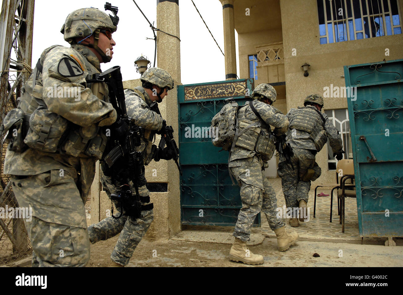 U.S. and Iraqi Army soldiers rushing into a house as they conduct a cordon and search in Kahn Bani Sahd, Iraq. Stock Photo