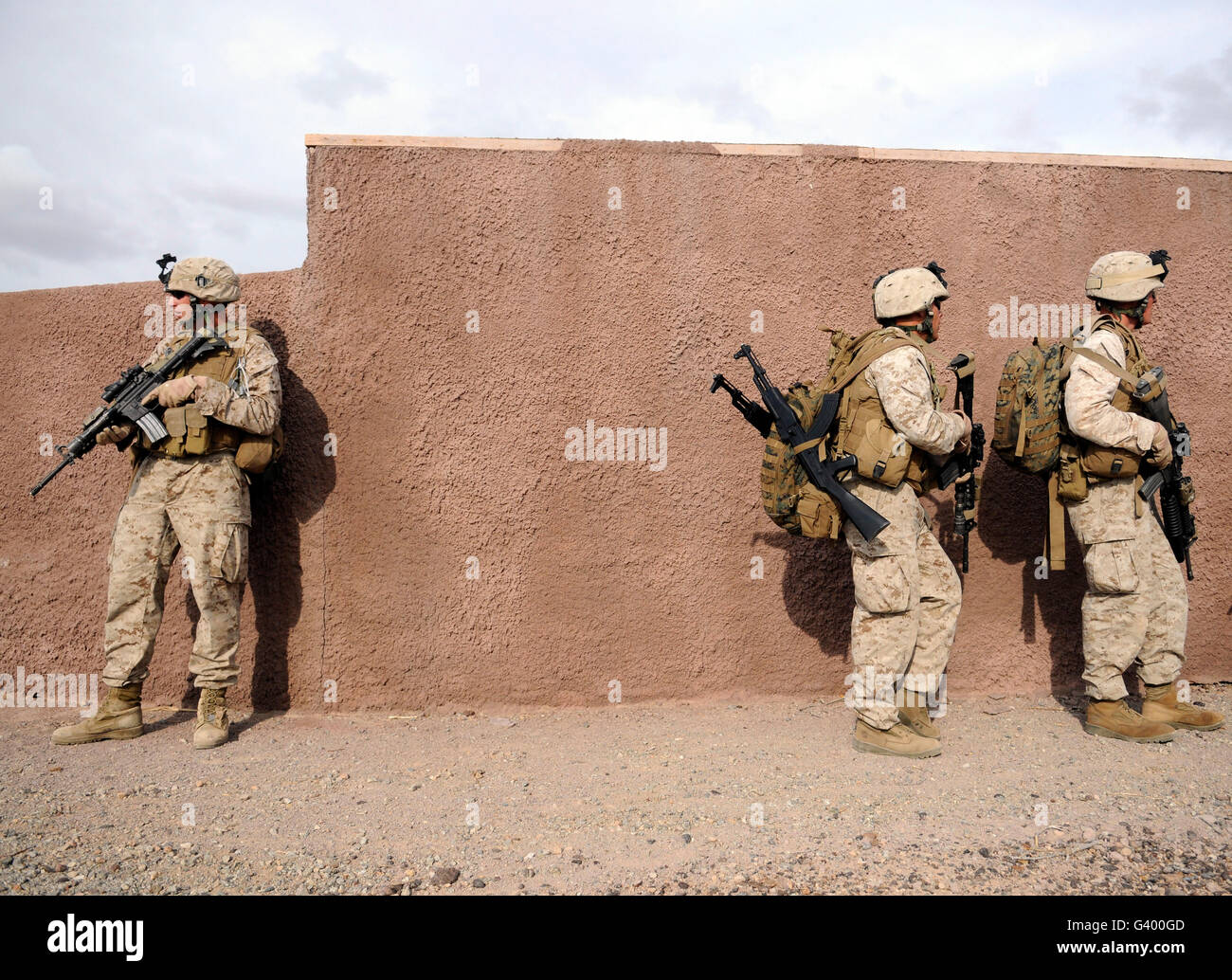 Soldiers halt behind a wall moments before rushing to a landing site for extraction. Stock Photo