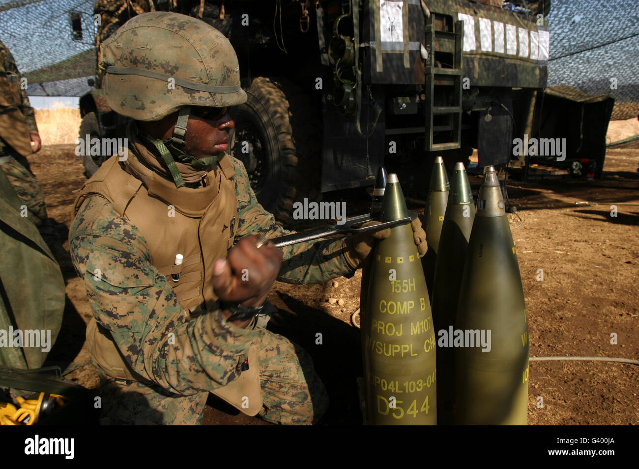 An artilleryman places a fuse on a 155mm projectile using an M18 fuse setter. Stock Photo