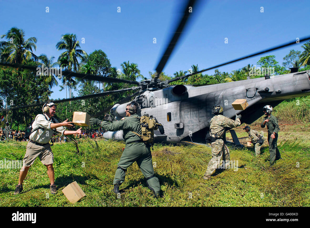 U.S. Airmen and Marines unload relief supplies from a CH-53E Super Stallion helicopter in Indonesia. Stock Photo
