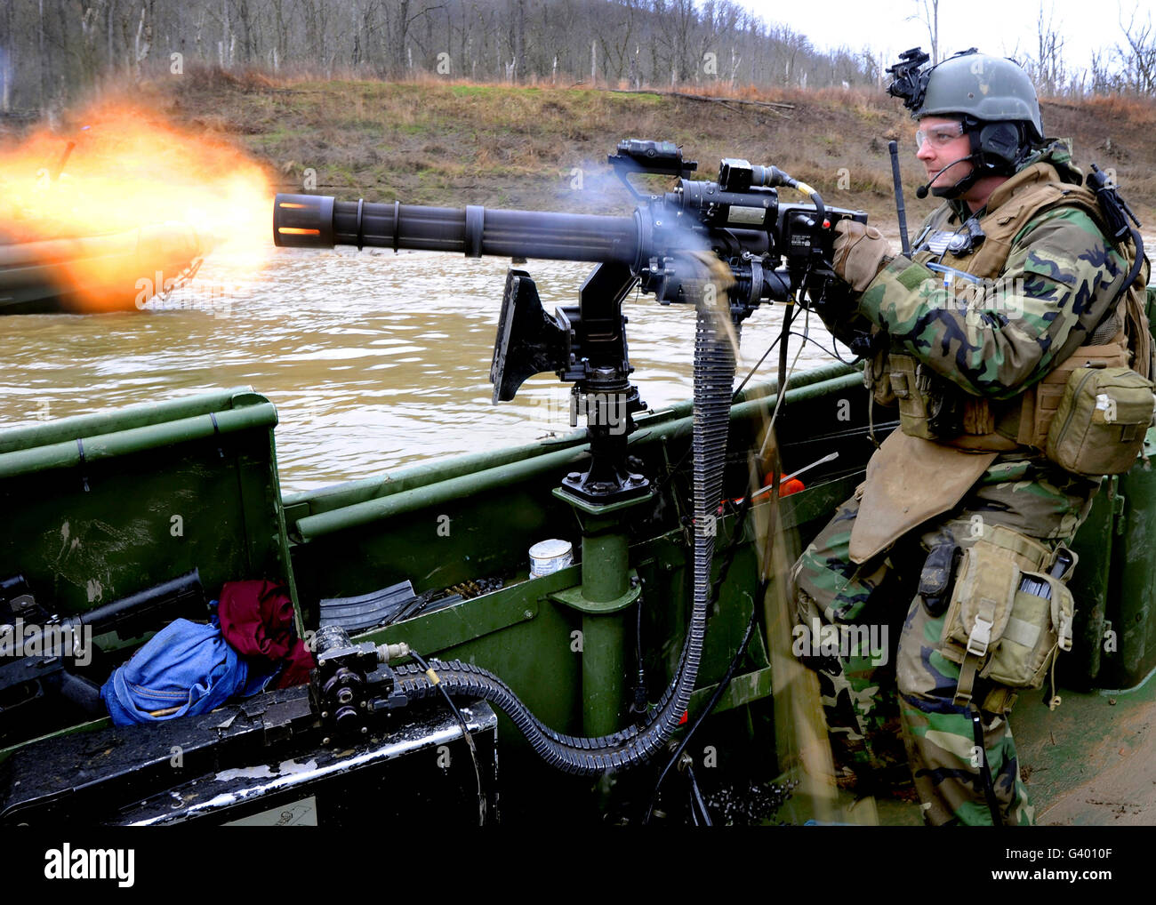 Gunner's Mate fires a GAU-17A gun from the bow of a riverine assault boat. Stock Photo
