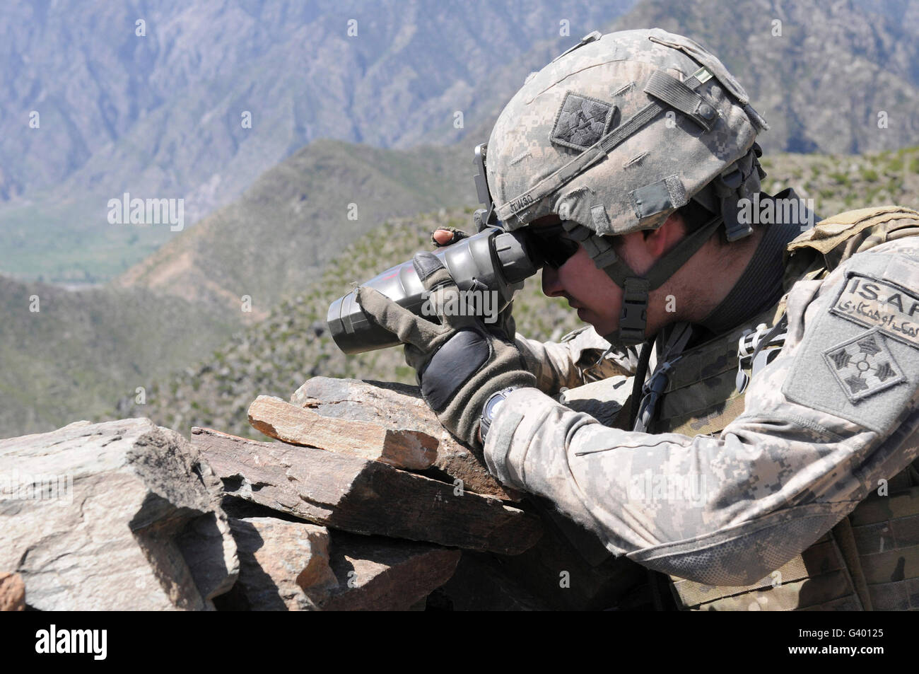 U.S. Army soldier monitors an Afghan National Army visit to Nishigam village in Afghanistan. Stock Photo