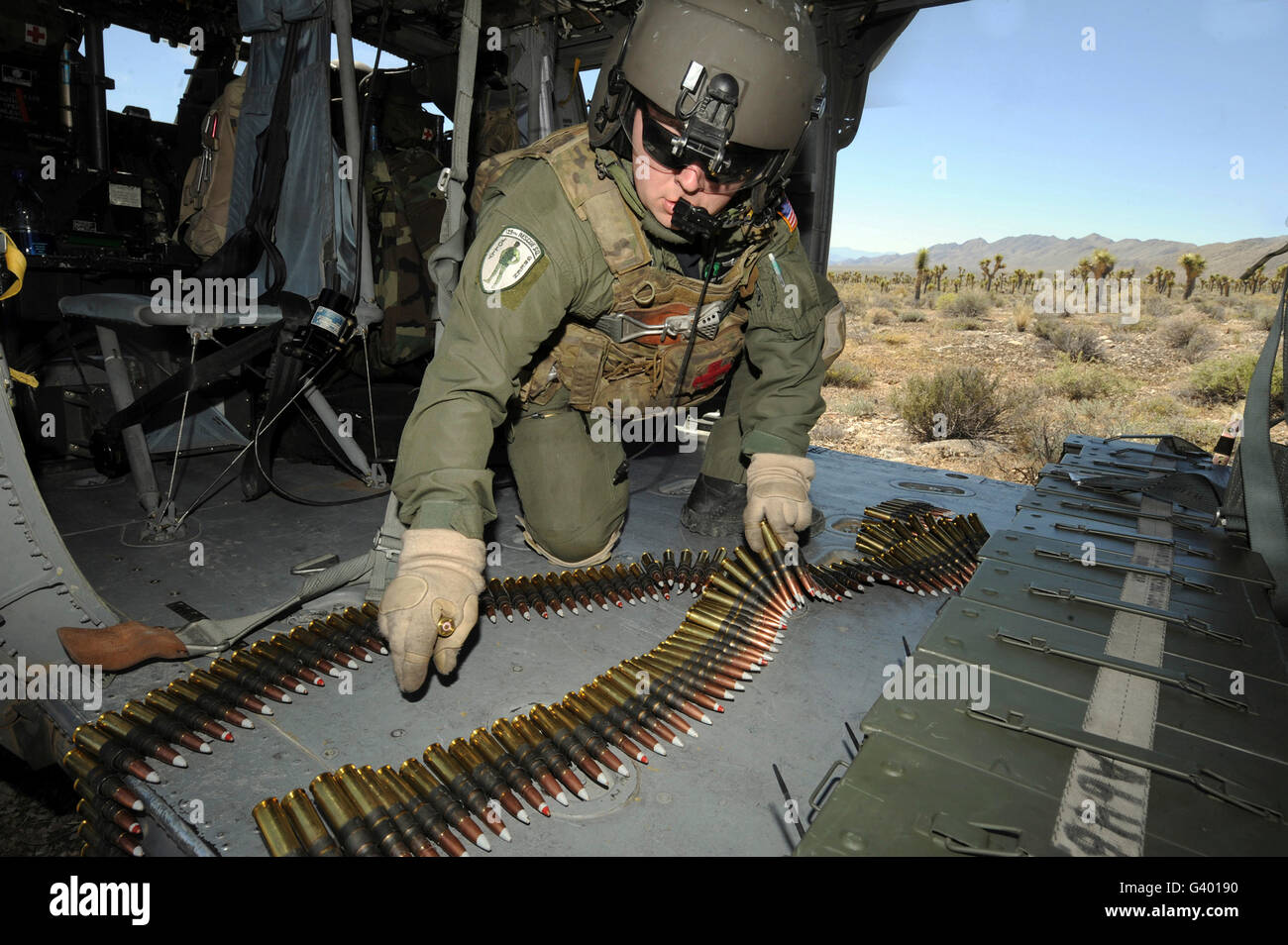 A soldier checks the ammo belt for a .50-caliber machine gun on board an HH-60G Pave Hawk. Stock Photo
