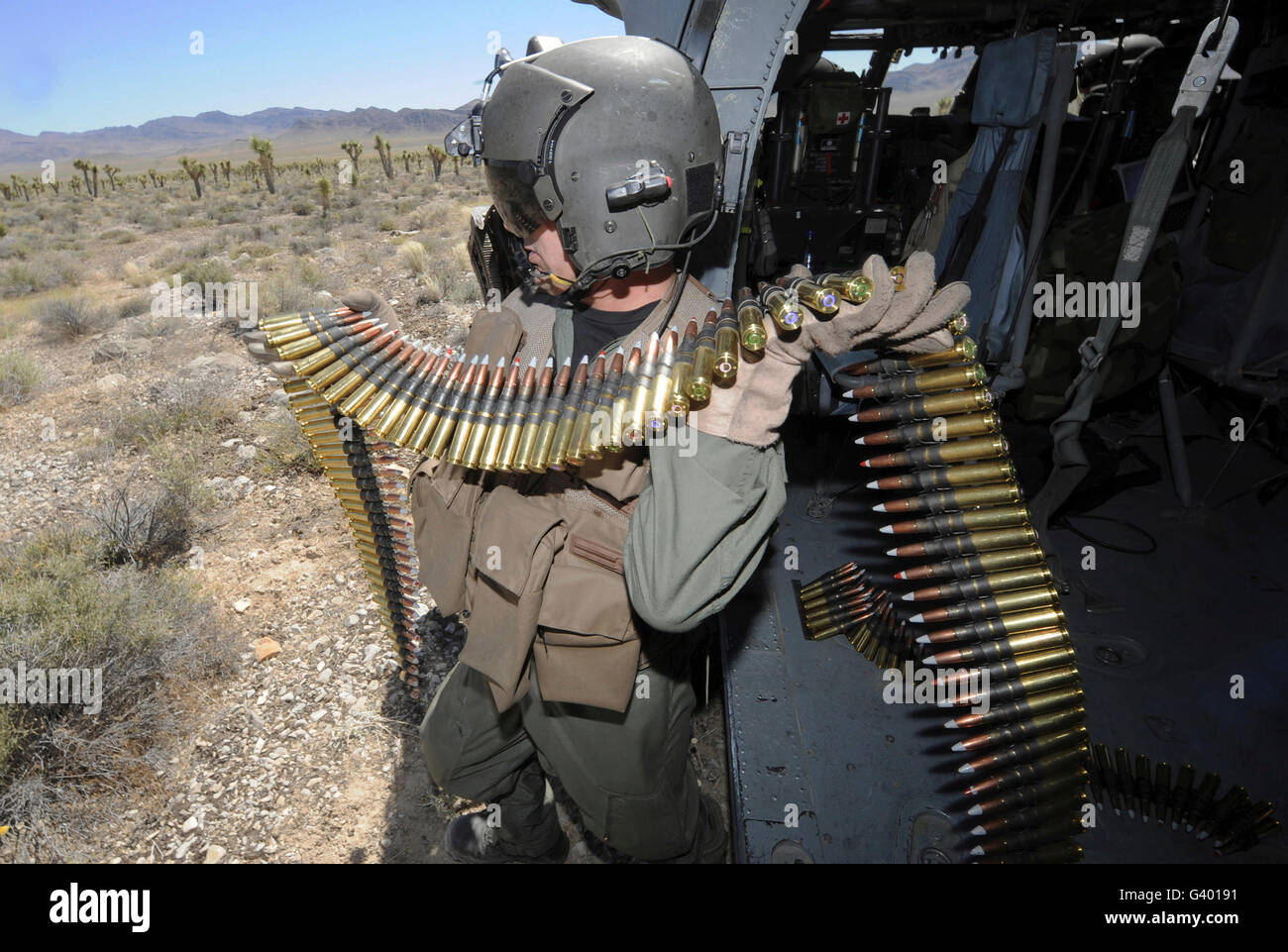 A soldier carries .50 caliber machine gun ammo to reload from an HH-60 Pave Hawk. Stock Photo