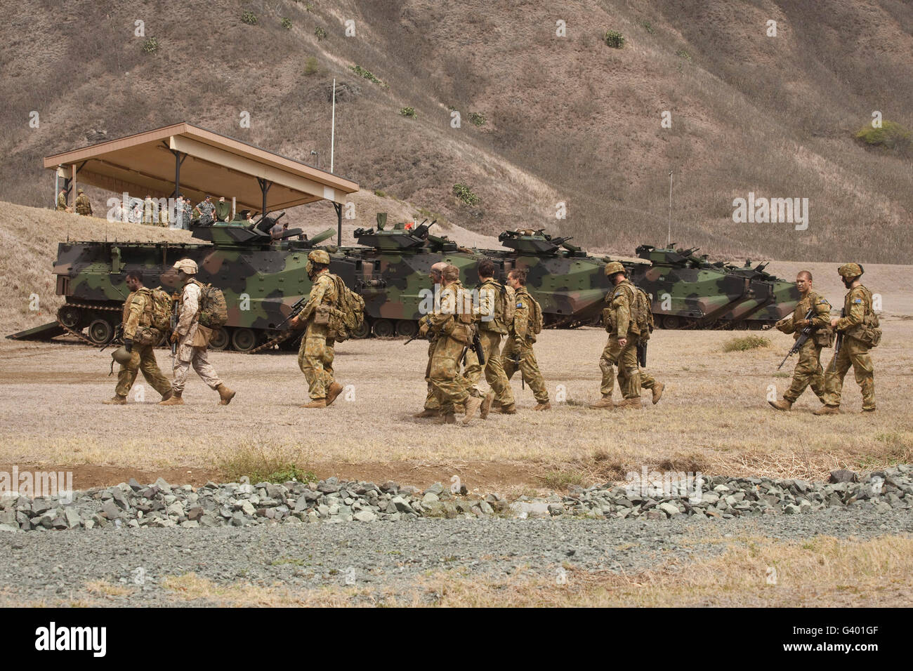 A U.S. Marine and Australian soldiers walk past amphibious assault vehicles they used during a raid. Stock Photo
