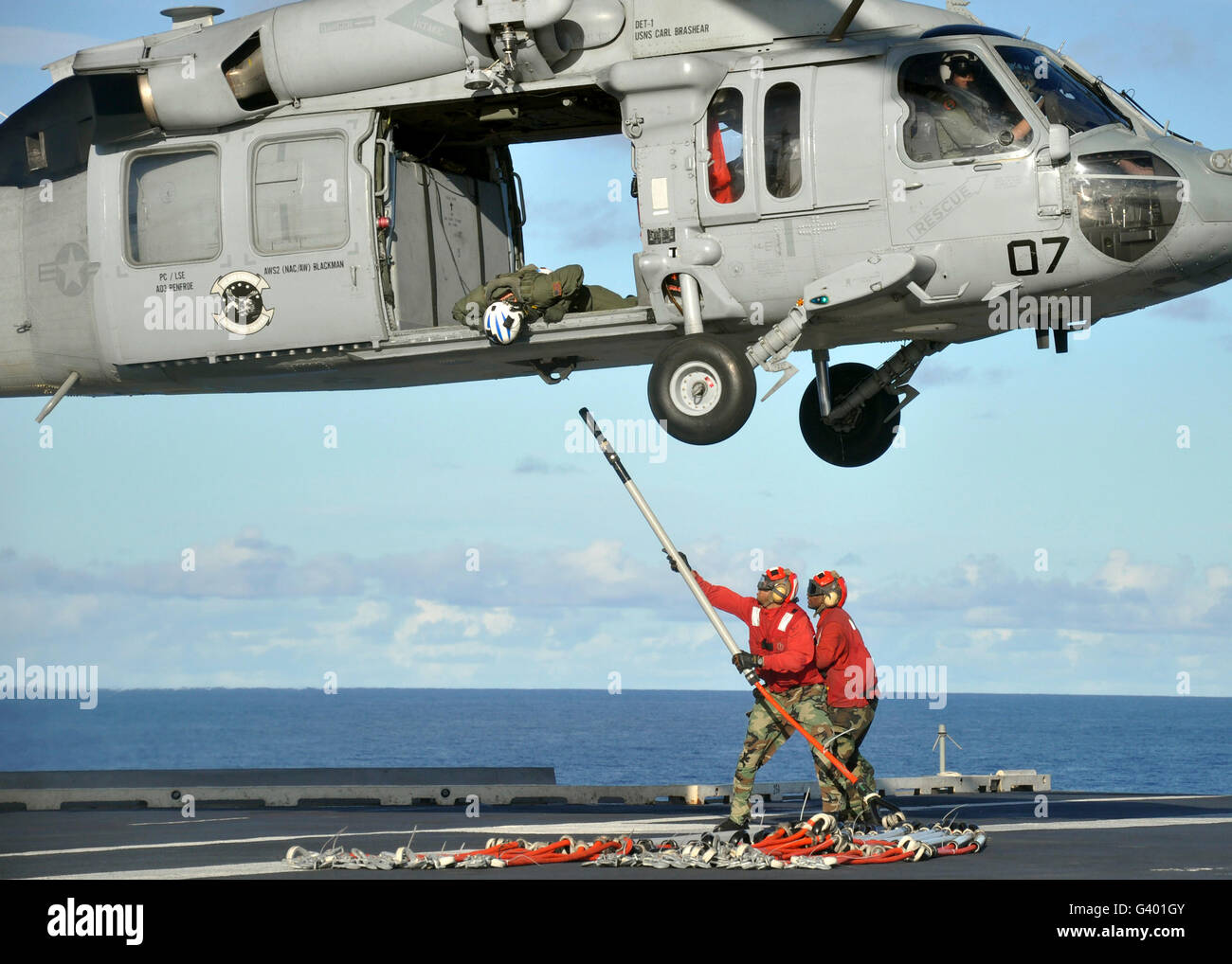 Aviation Ordnancemen hook a pallet sling onto an MH-60S Sea Hawk helicopter. Stock Photo