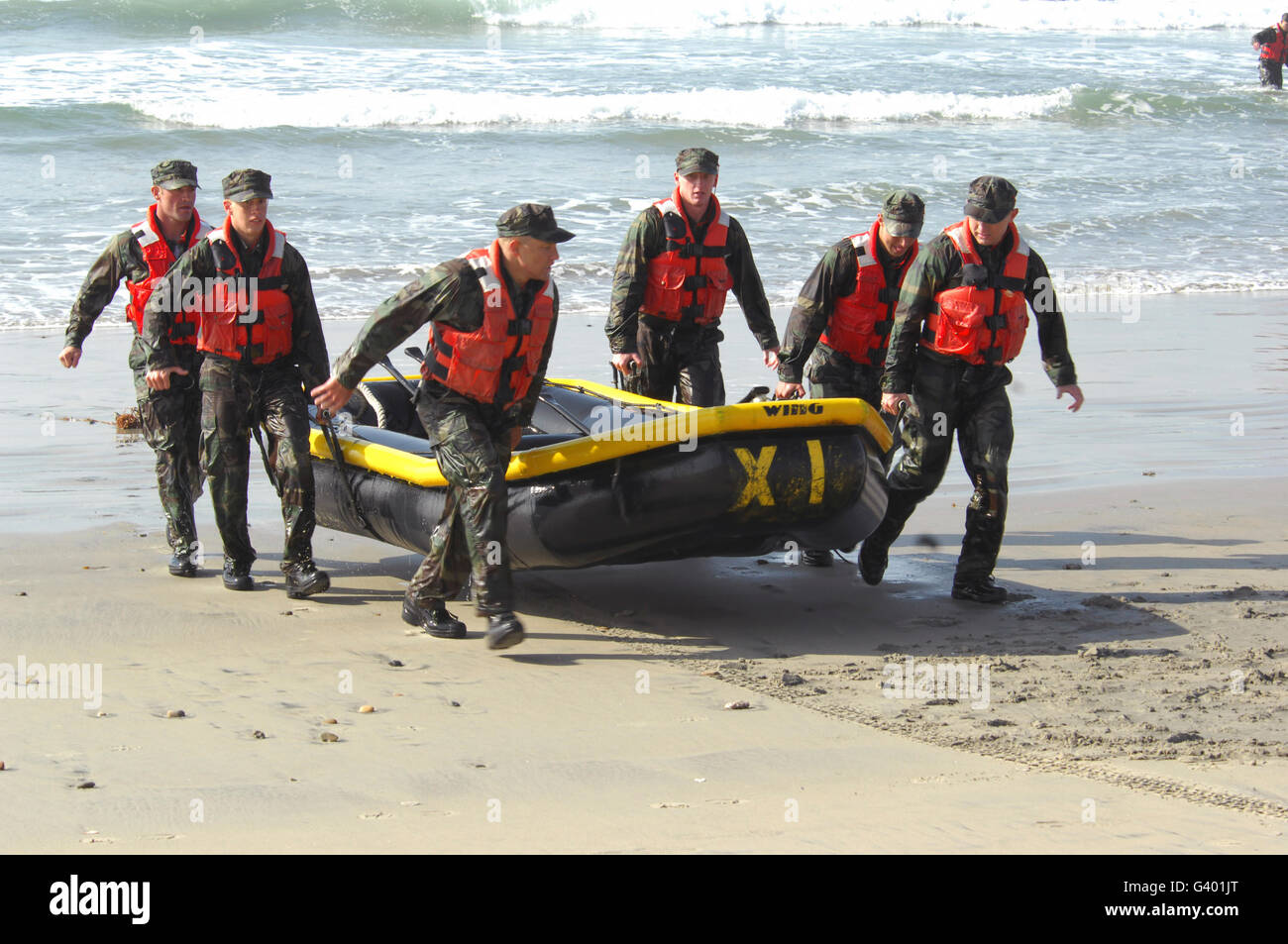 Basic Underwater Demolition/SEAL students bring their boat out from the water. Stock Photo