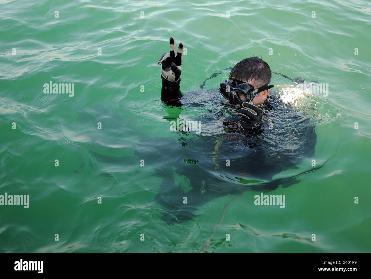 U.S. Navy diver signals before diving underwater. Stock Photo