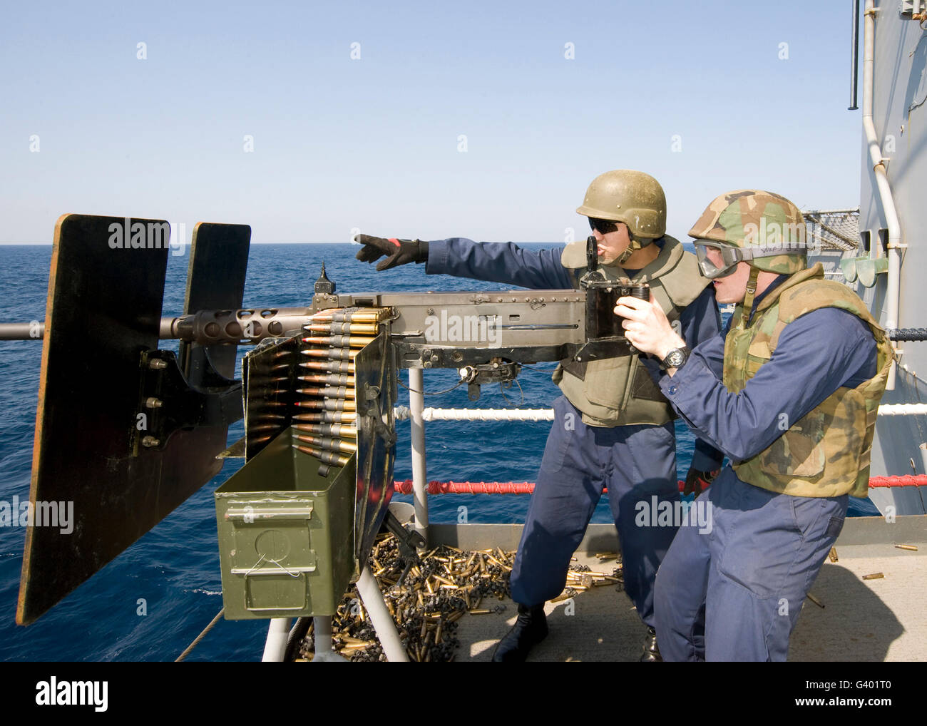 Gunner's Mate's fire a .50-caliber machine gun aboard an aircraft carrier. Stock Photo