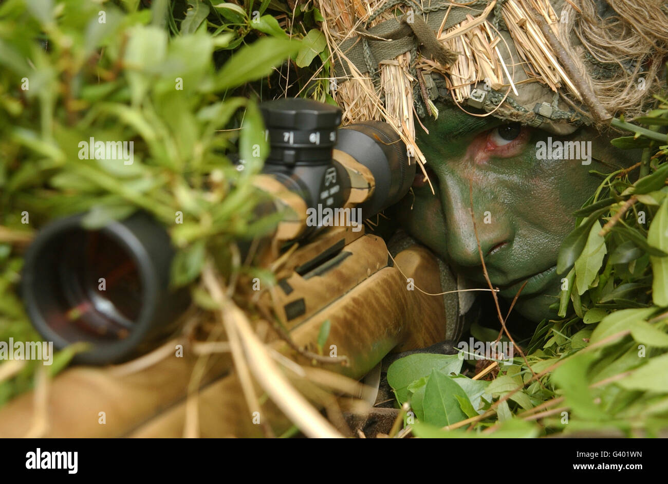 A sniper dressed in a ghillie suit stalks his enemy Stock Photo